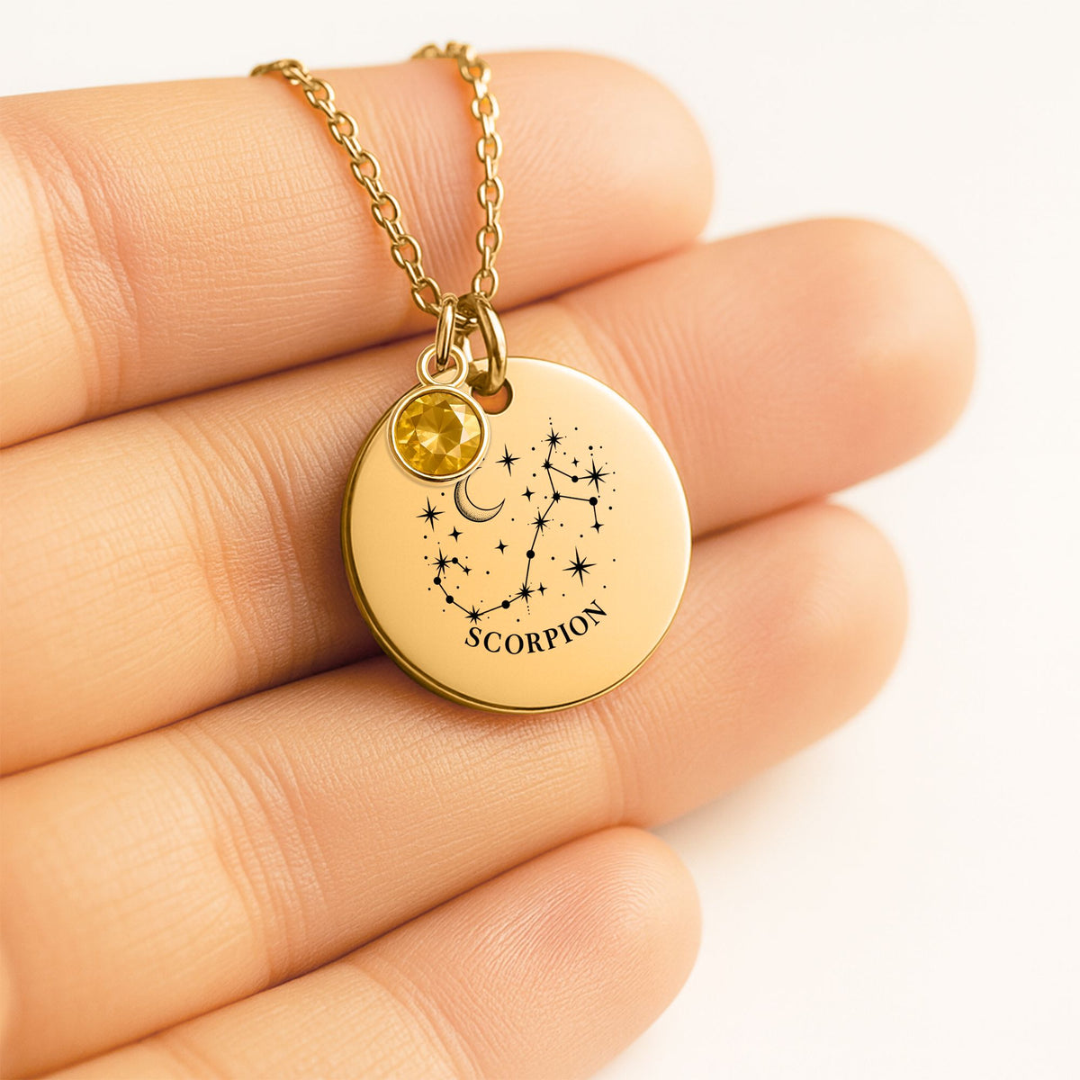 Médaille ronde gravée de la constellation Scorpion, tenue dans la main, avec pierre de naissance