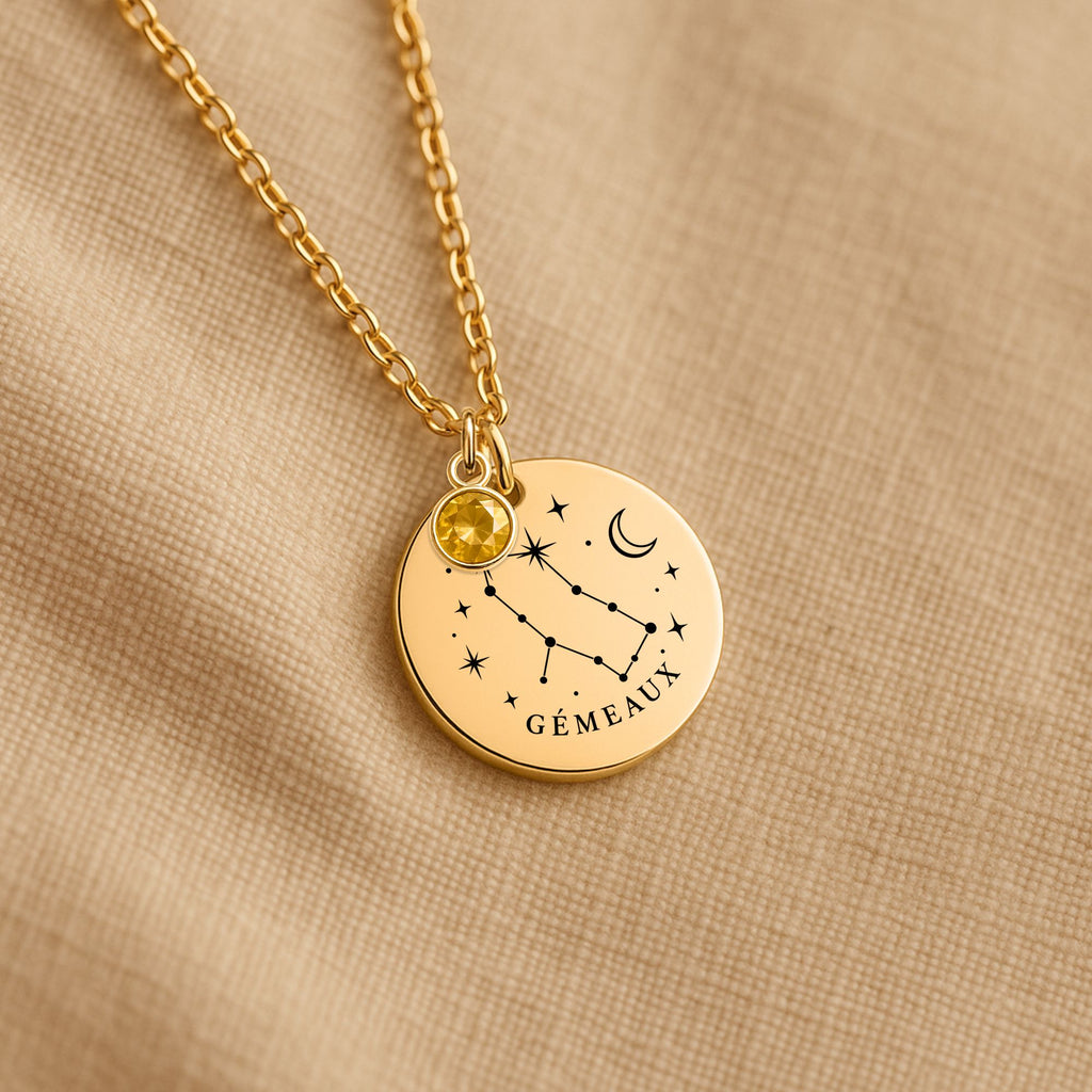 Détail de la médaille constellation Gémeaux et de sa chaîne sur un tissu beige