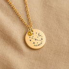 Détail de la médaille constellation Taureau et de sa chaîne sur un tissu beige
