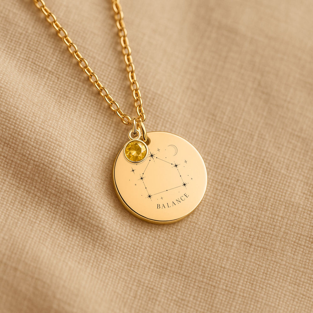 Détail de la médaille constellation Balance et de sa chaîne sur un tissu beige
