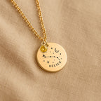 Détail de la médaille constellation Bélier et de sa chaîne sur un tissu beige