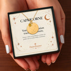 Collier constellation Capricorne dans son coffret avec carte-message, tenu à la main